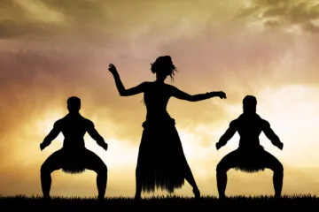 3 people making the typical Maori dance at sunset