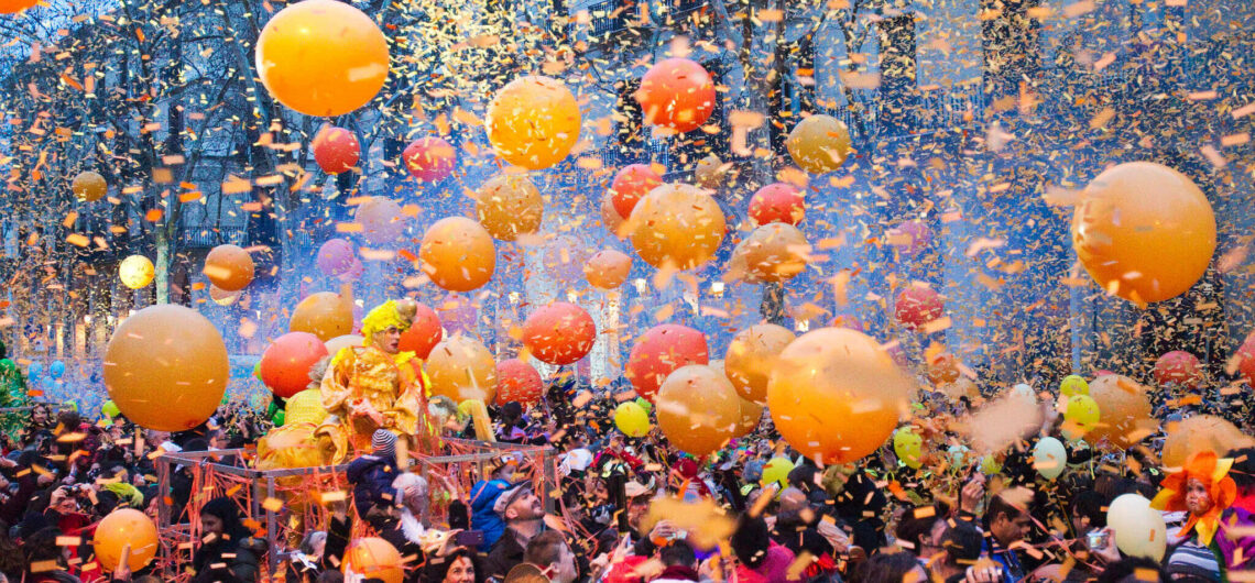 A crowd joyfully playing with orange balloons in Barcelona.